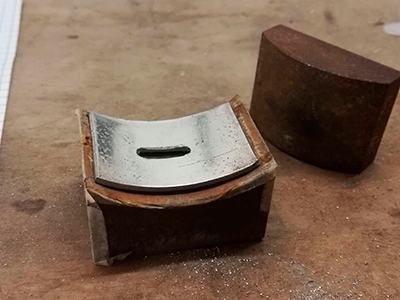 Trinn 26: Plasser tinnplaten i en stålklump med Ø75 mm og bank så tinnplaten får en rund form
